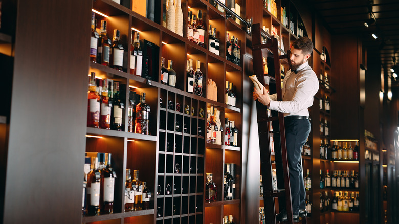 man on ladder behind bar