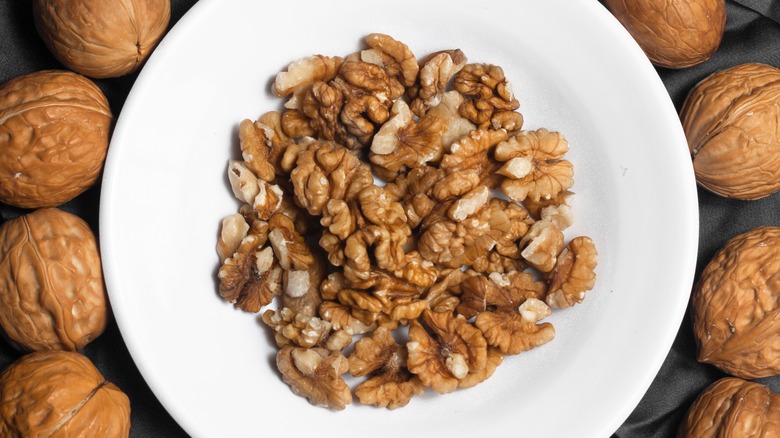 Bowl of chopped walnuts with whole walnuts