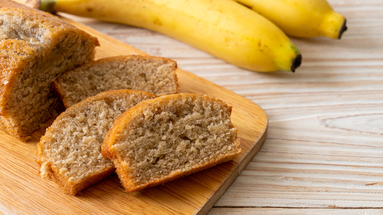 Banana bread slices next to bananas 