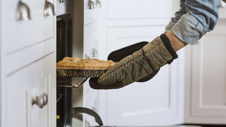 Hands putting pie in the oven