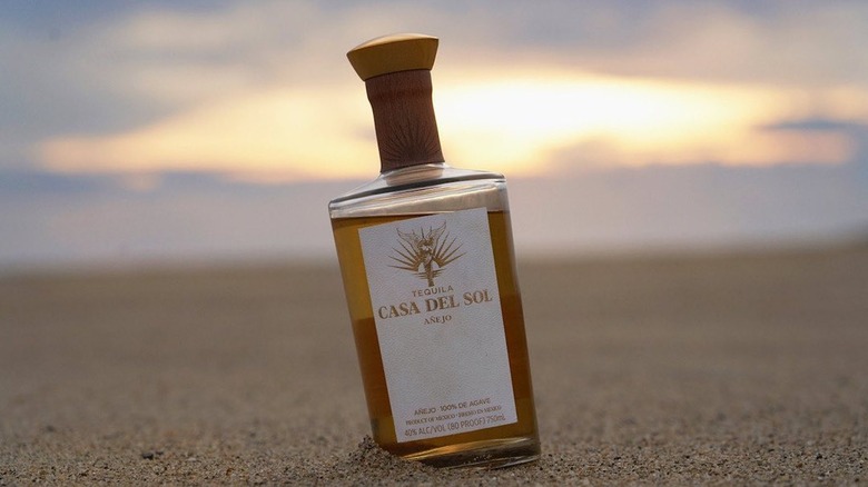 bottle of Casa Del Sol tequila on beach