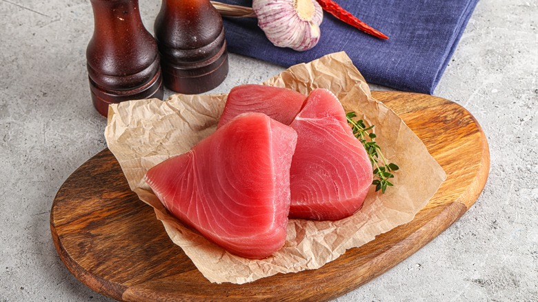 Raw tuna steaks and thyme on cutting board