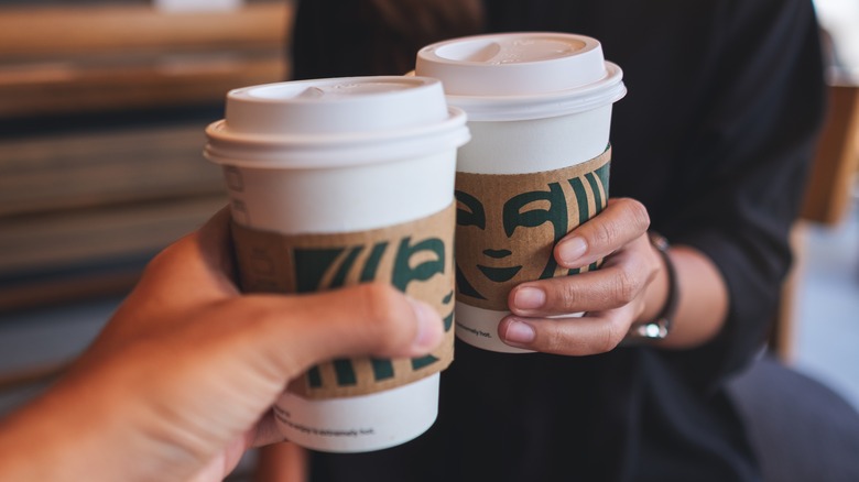 Two people holding Starbucks drinks