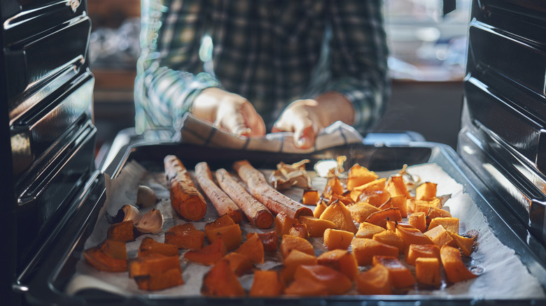 Person taking roast vegetables out of oven