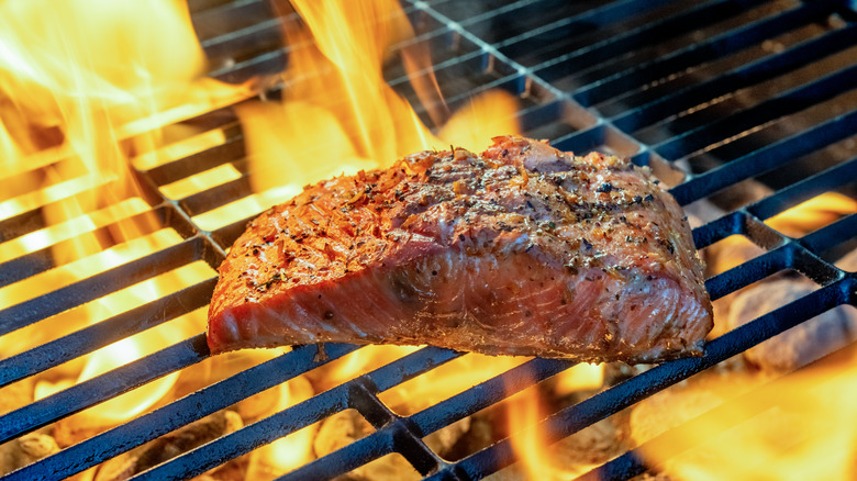 Salmon filet cooking on grill with flames