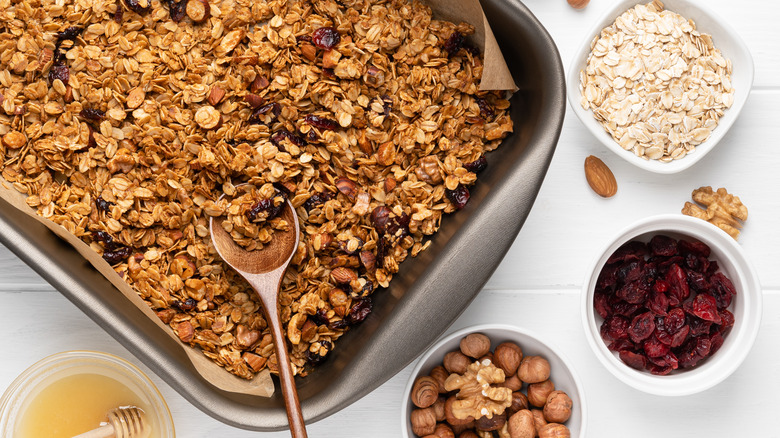 Pan of baked granola with bowls of honey and dried fruit