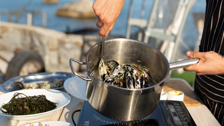 Chef stirring mussels in pot