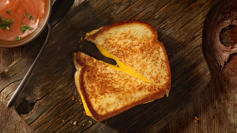 grilled cheese and cup of tomato soup on wood board