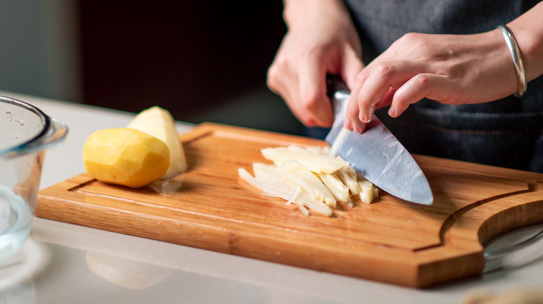 Woman cutting potatoes for fries