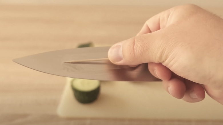 Man taping toothpick to a knife