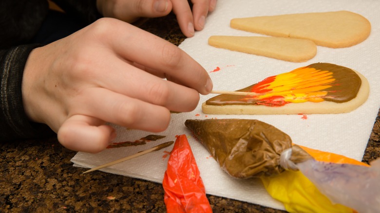 Hand using toothpick on cookie