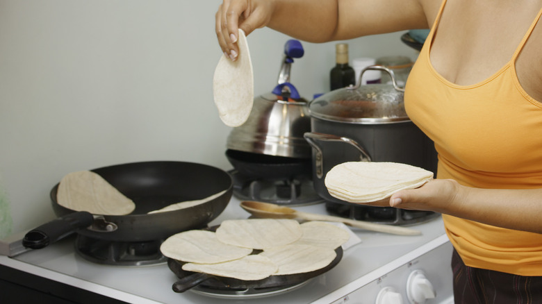 woman frying tortillas on stove