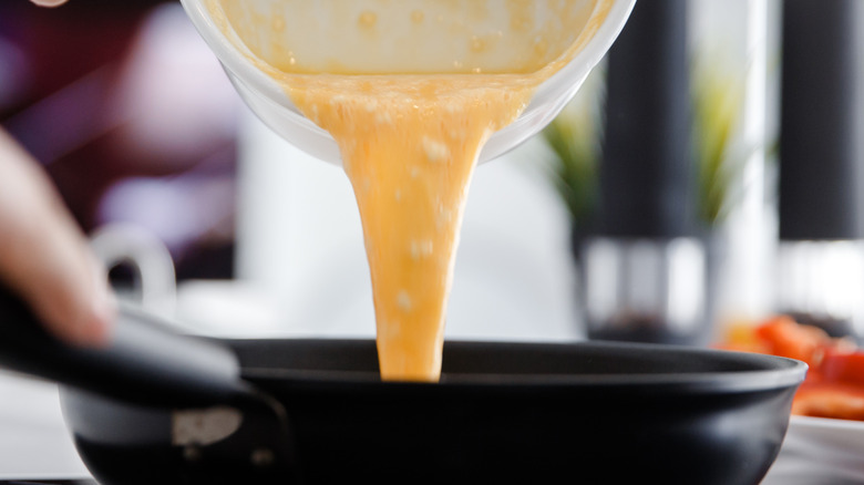 pouring beaten eggs into skillet