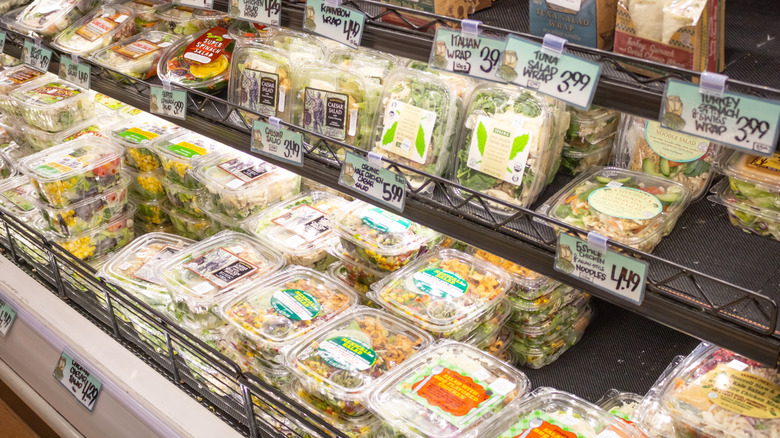 Trader Joe's pre-made salads sit on the shelves in the refrigerated section of the store.