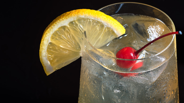 Tom Collins cocktail garnished with a cherry and lemon slice