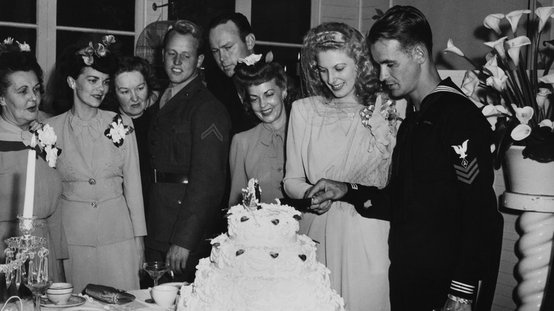 Couple cut into wedding cake in 1944, groom in military attire