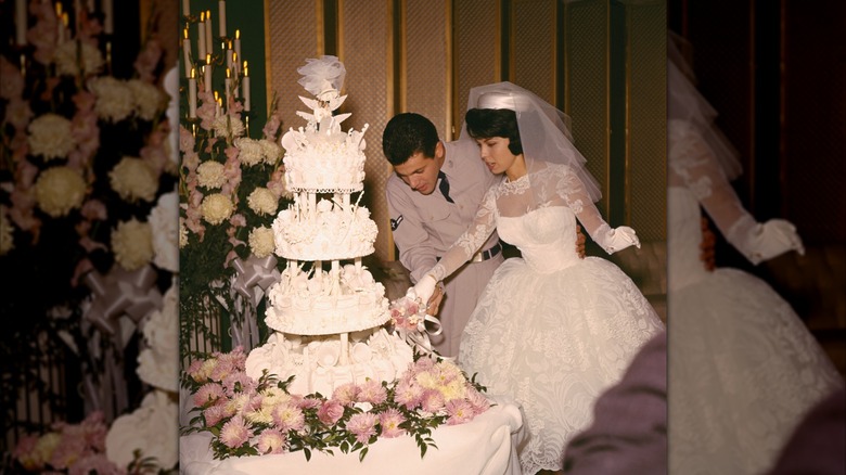 Nancy Sinatra and Tommy Sands cutting wedding cake in 1960