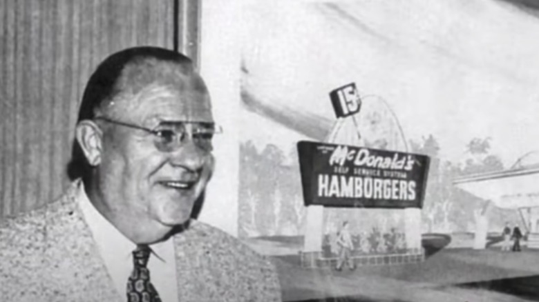 Dick McDonald in front of image of an early McDonald's