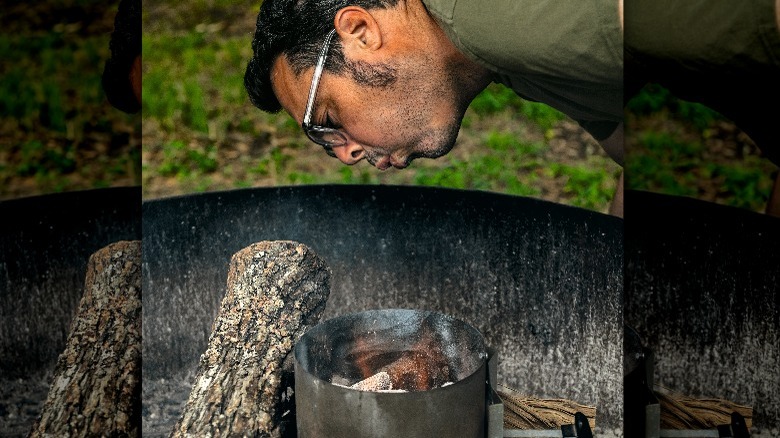 Aaron Franklin blowing on smoke from grill