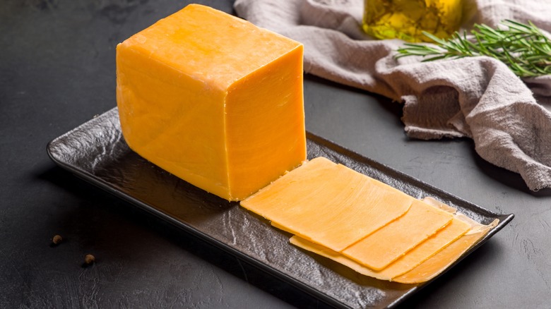 block of cheddar cheese with slices