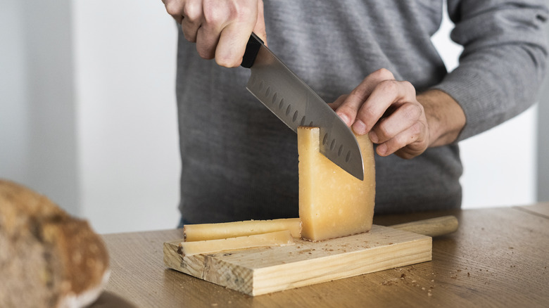 man cutting cheese on a cutting board