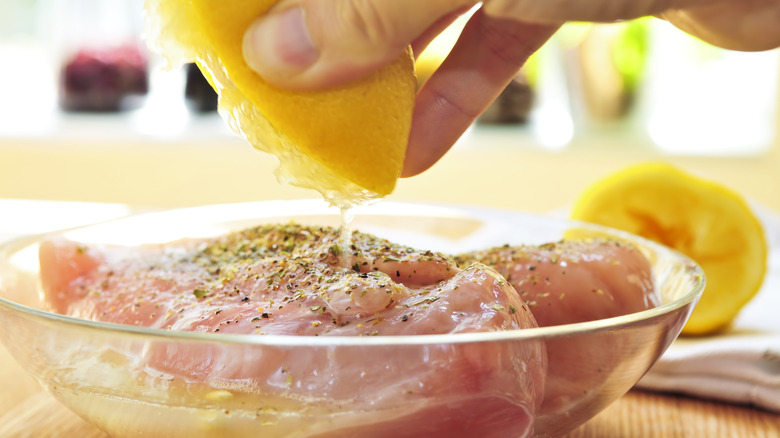 hand squeezing lemon on chicken