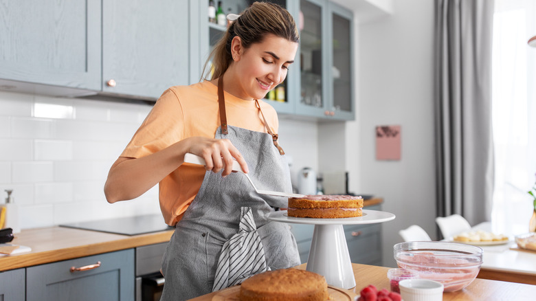 a woman frosts a cake