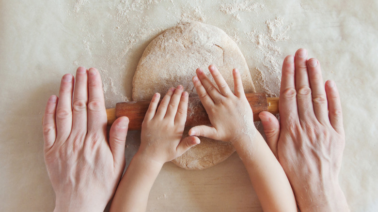 Parent and child rolling out dough