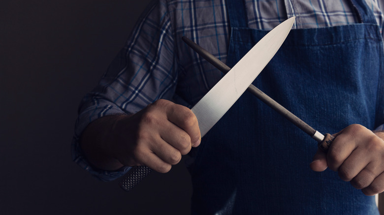 Knife and steel sharpener in hands