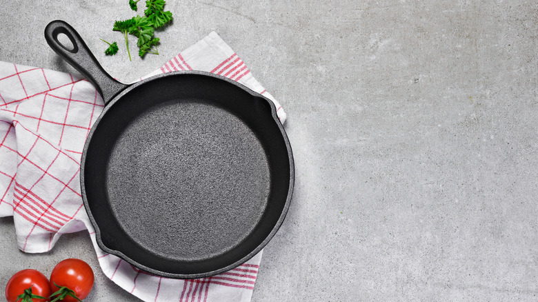 empty cast iron pan on a towel with herbs and tomatoes