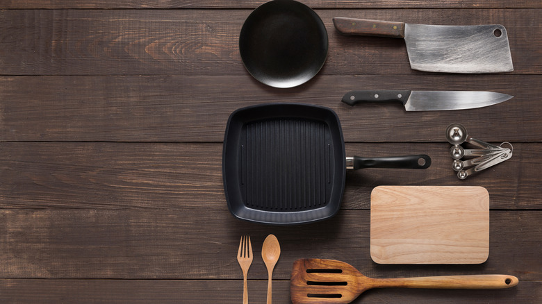 Cast iron pan on wood with various cooking utensils