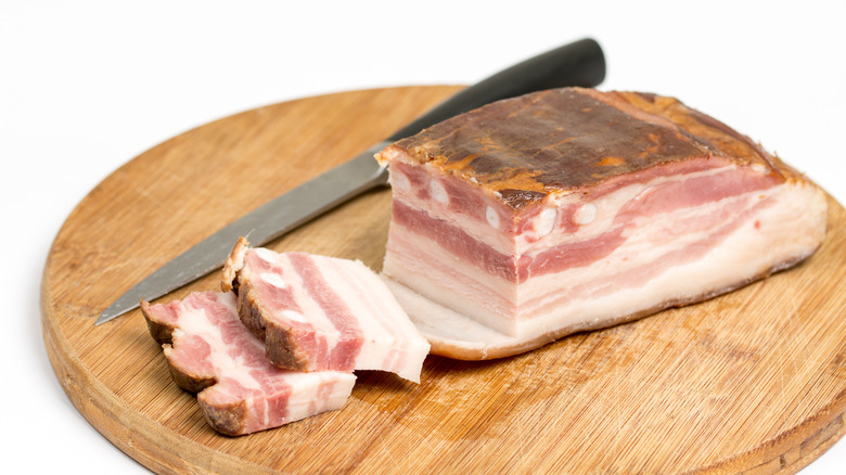 Uncured pancetta slices on a board