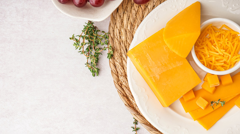 Plate of whole cheese and cheddar shreds with thyme and grapes