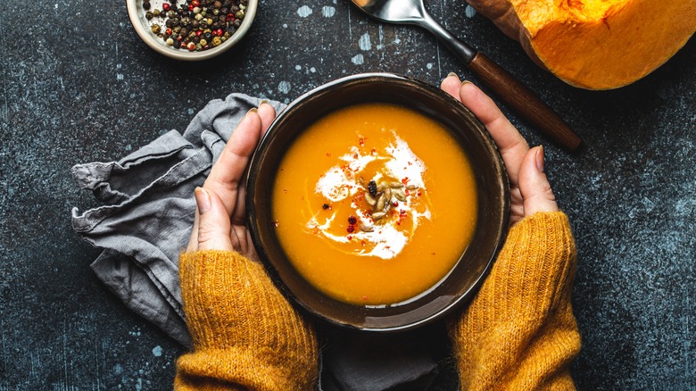 hands holding butternut squash soup