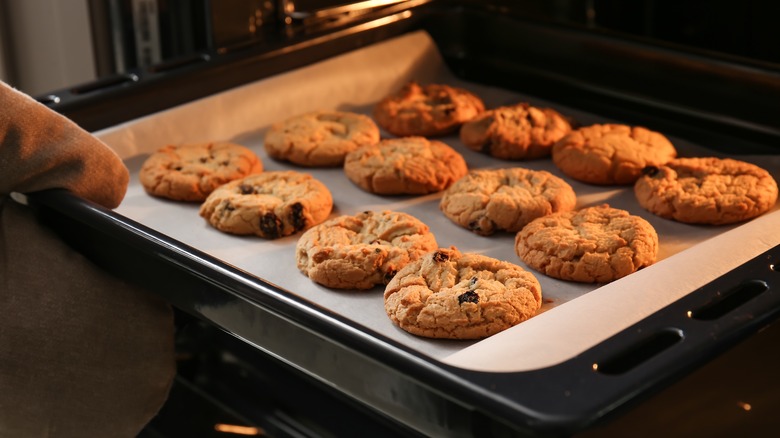 hand pulling cookies from oven