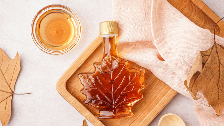 bowl and jar of maple syrup with dried leaves