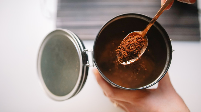 hand holding spoon of coffee powder