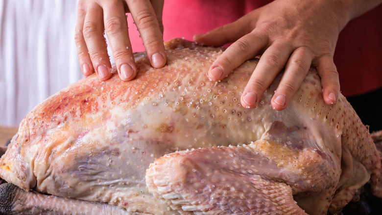 hands rubbing salt on turkey