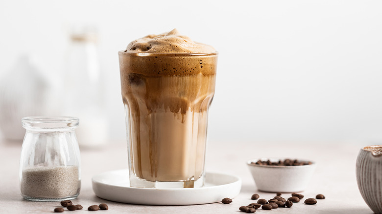 A glass of iced coffee is topped with cold foam.