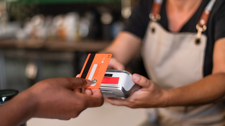 A person pays with a card at the bar.