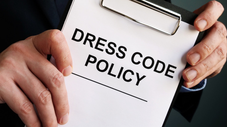 person holding dress code policy paper