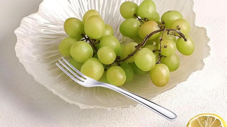 A fruit fork in a bowl with grapes