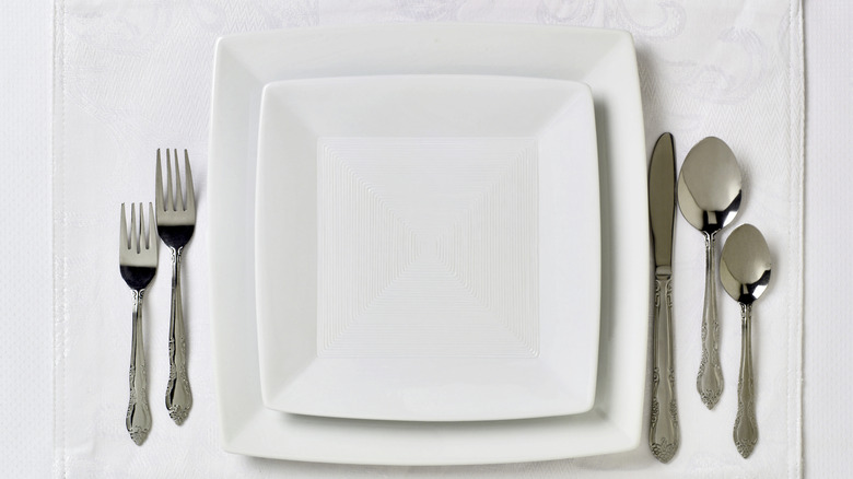 Utensils set around a white plate