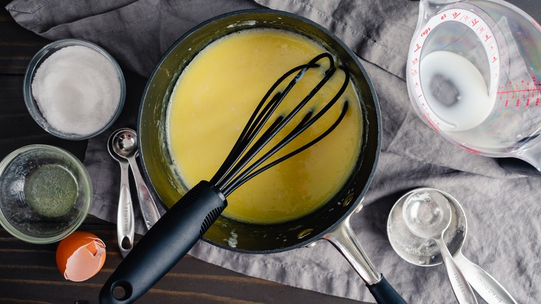 saucepan with a black whisk and freshly made tangzhong roux surrounded with ingredients and kitchen equipment