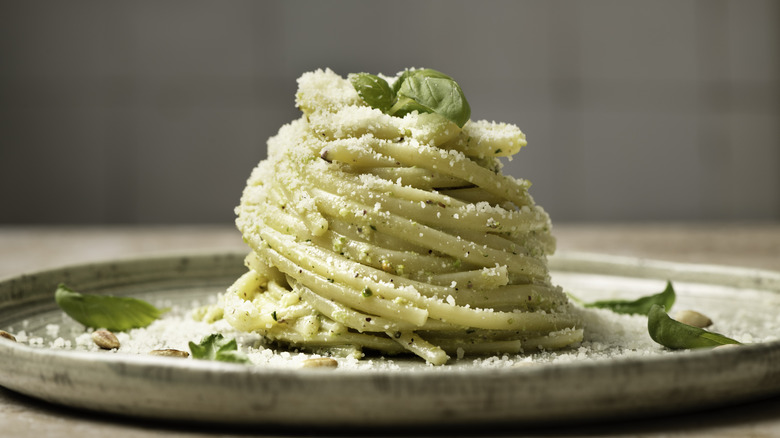 Twirled pile of pasta on a plate garnished with basil and parmesan cheese