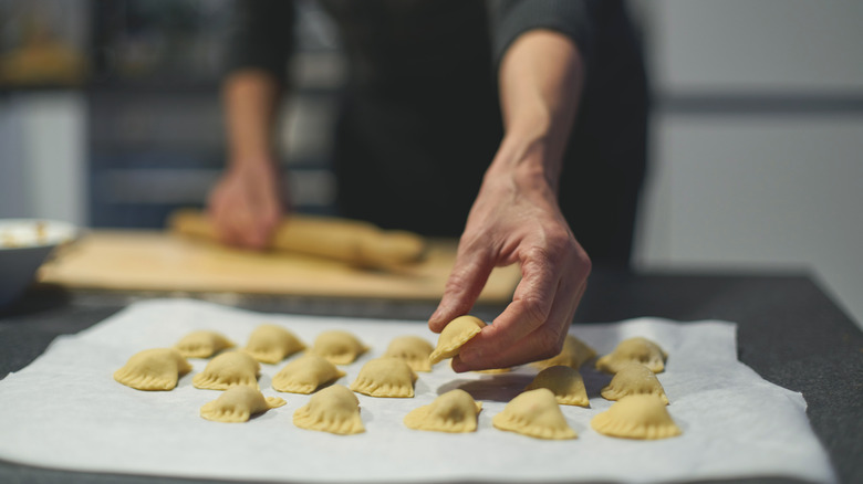 Man laying out fresh ravioli on a layer of baking paper to dry