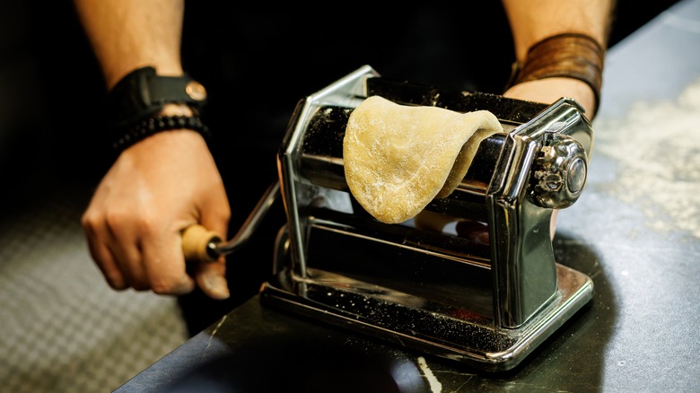 Man making a layer of pasta dough with a pasta machine