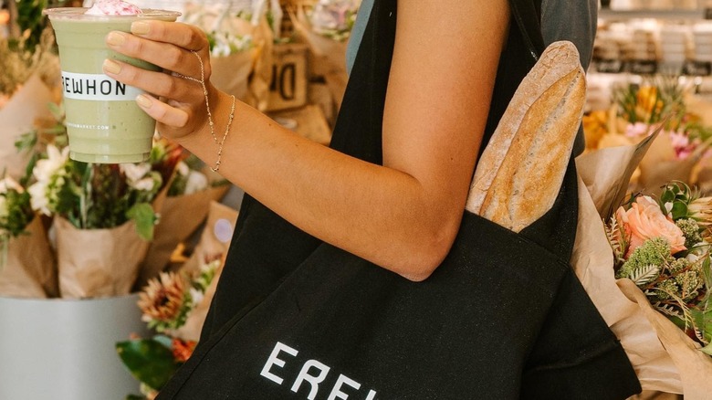 Erewhon shopper with smoothie, merch, and baguette