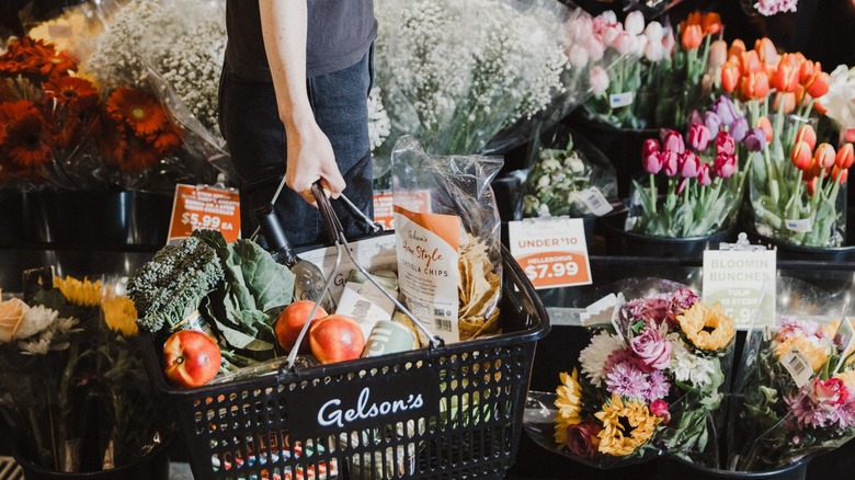 A person with a full Gelson's basket in the floral department