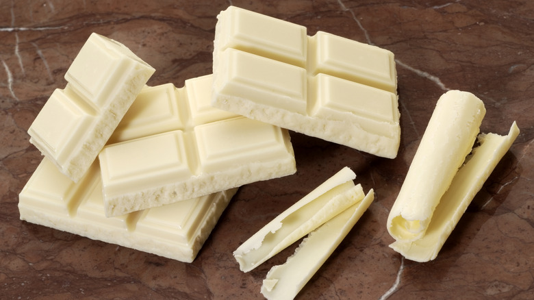 white chocolate bar chunks with white chocolate curls placed on a red marble counter